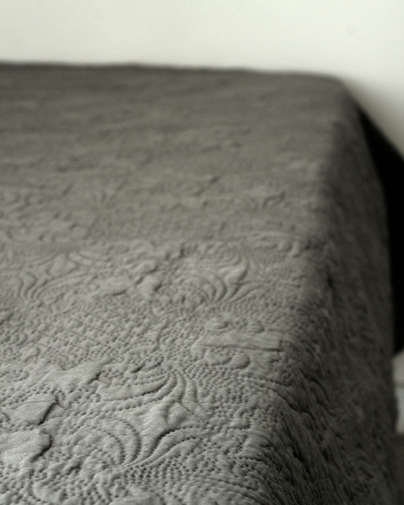 Close-up of a charcoal stitch-quilted bedspread