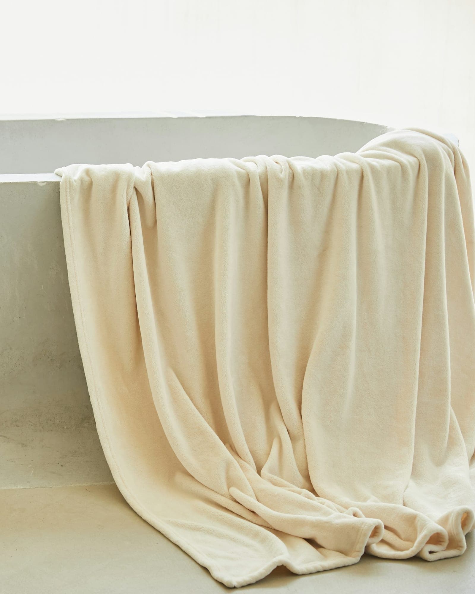 Ivory bath towel draped over a freestanding bath