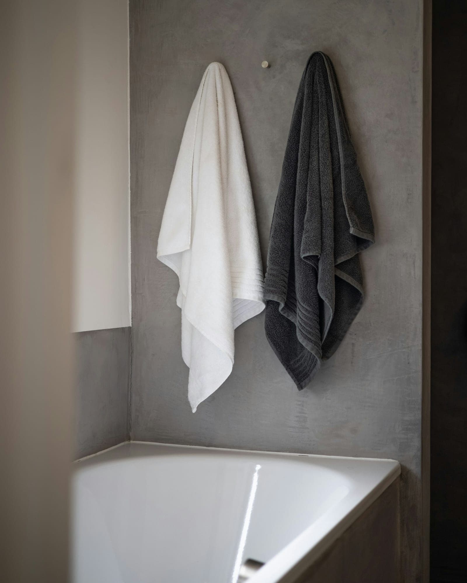 Charcoal and white bath towels hanging beside a bath