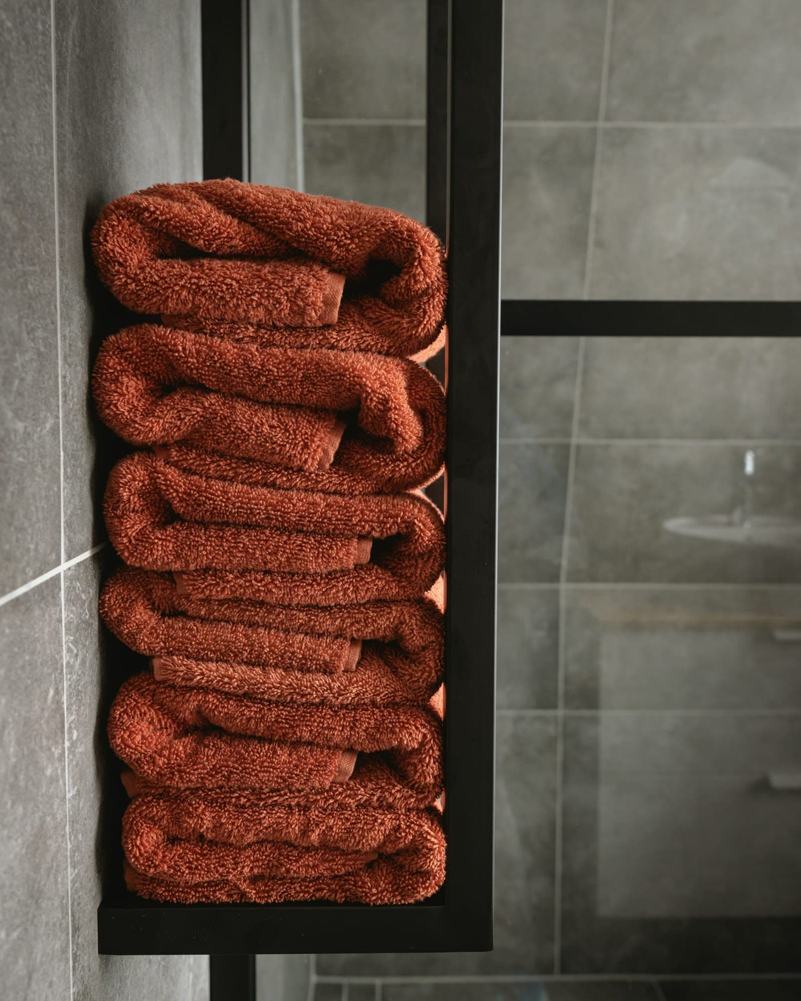 Terracotta towels rolled on a bathroom shelf
